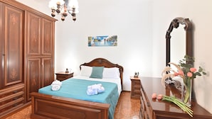 Un dormitorio con cama de madera, una mesita de noche, un aparador, un espejo y una araña.