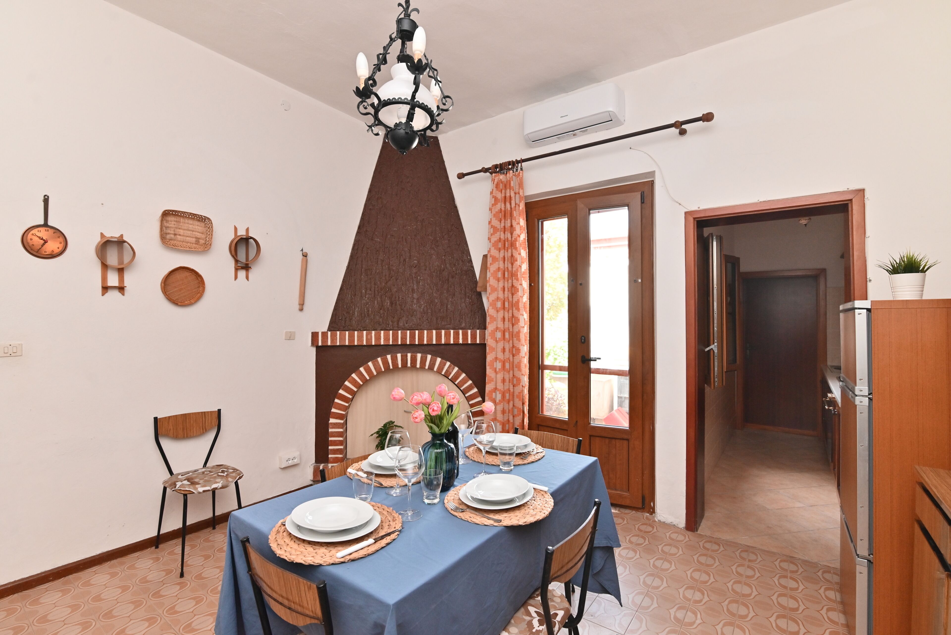 A dining area with a table set for four, a decorative wall with various items, a fireplace, and a door leading to another room.