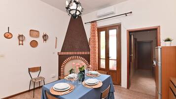 A dining area with a table set for four, a decorative wall with various items, a fireplace, and a door leading to another room.