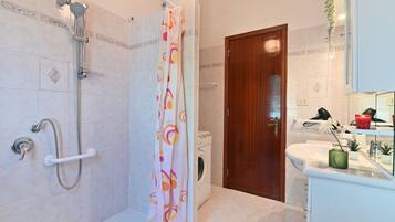 A bathroom with a shower, a toilet, a sink, and a mirror.