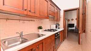 Una cocina con armarios de madera, un lavamanos de acero inoxidable, una estufa y un microondas.