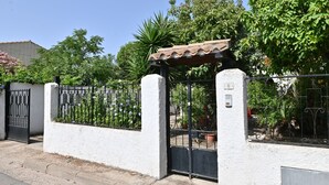 Propiedad resguardada por un muro blanco, una reja metálica y una estructura de techo con tejas.