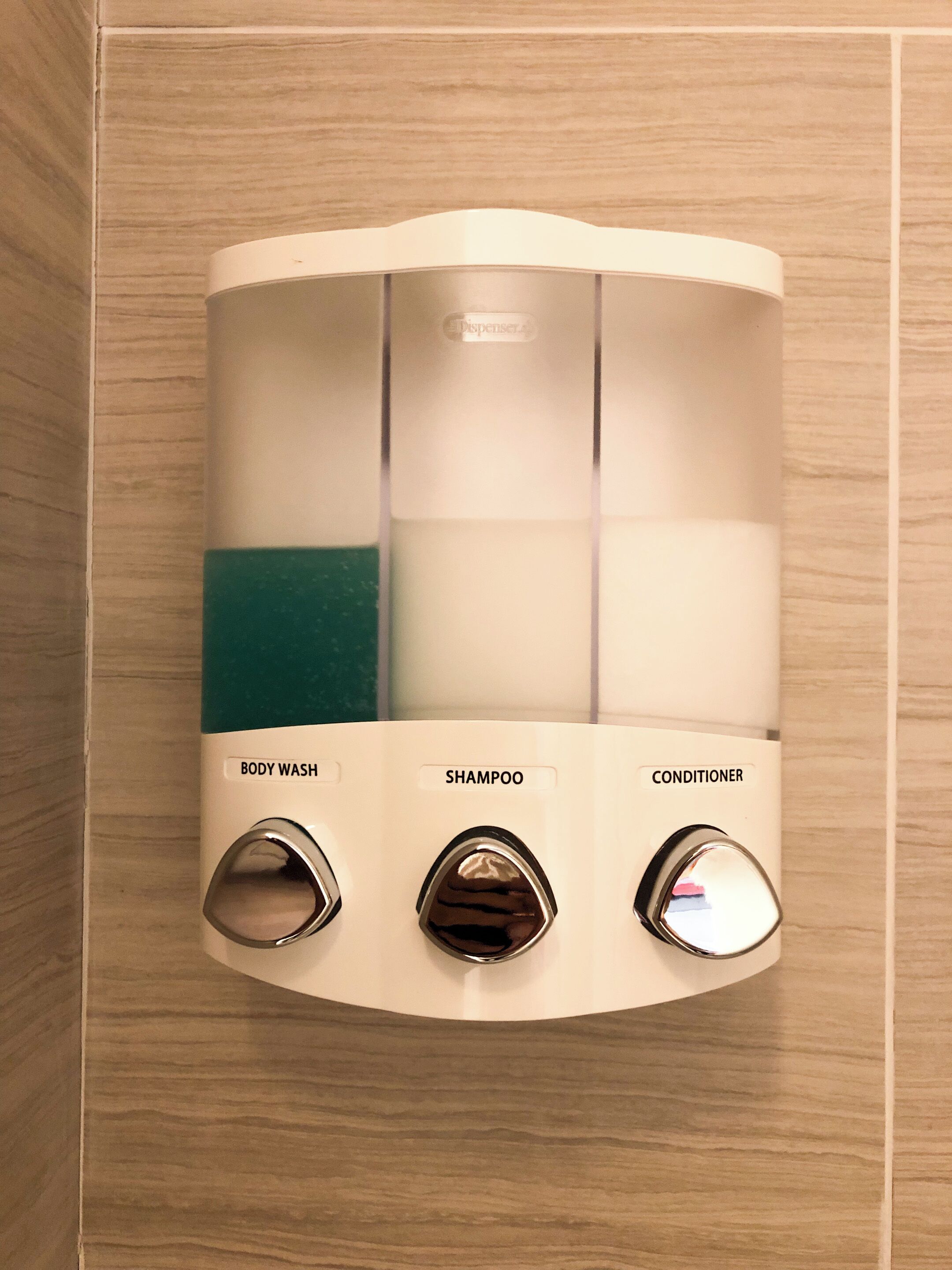 A wall-mounted dispenser with three compartments labeled body wash, shampoo, and conditioner.