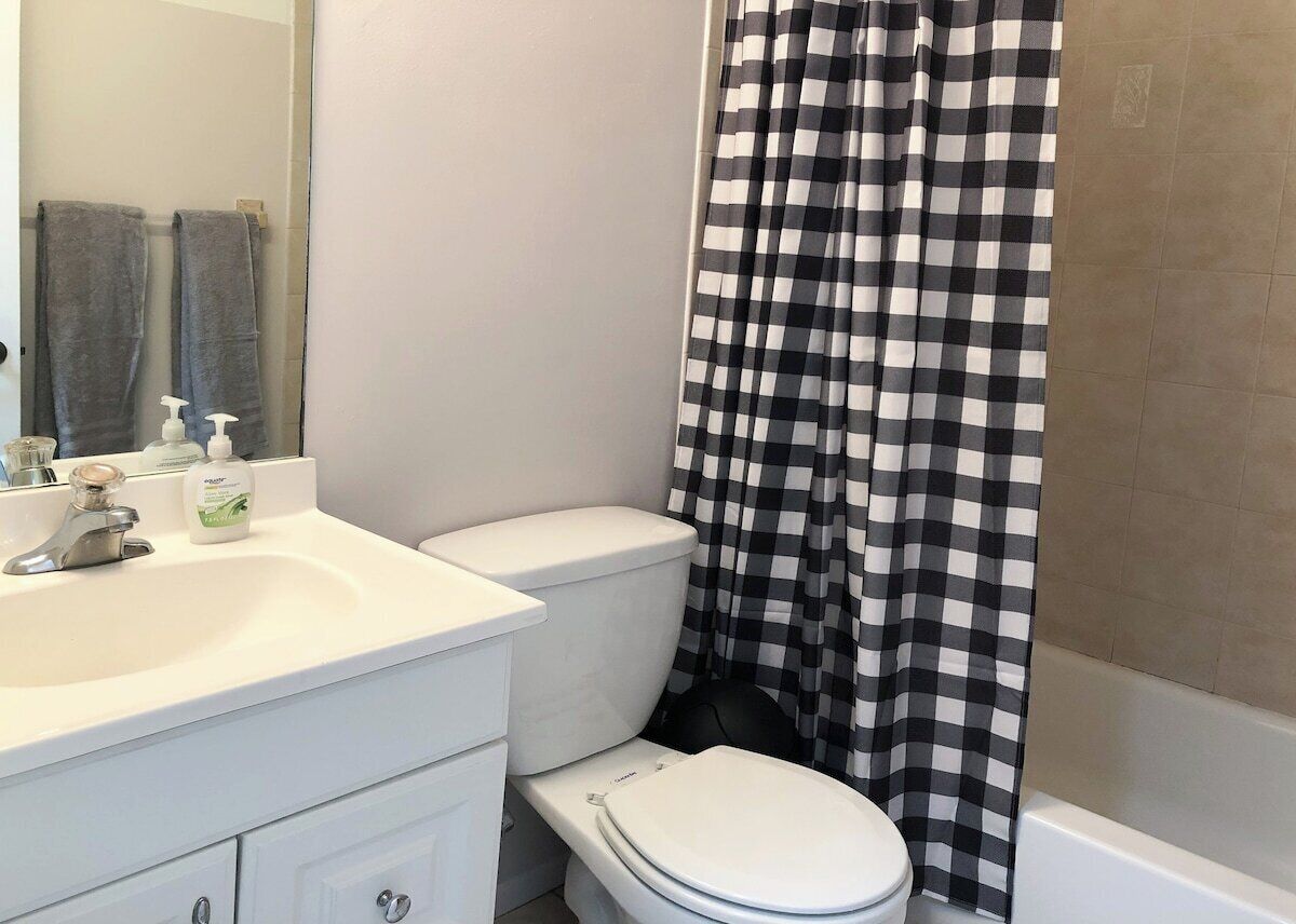 A bathroom with a white sink, a toilet, and a shower curtain.
