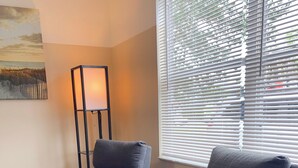 Two grey armchairs with red cushions, a floor lamp, and a window with blinds. - Lazy Cuckoo Inn (Fort Myers Beach)