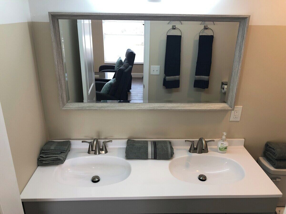 Un bagno con due lavandini, uno specchio grande e un porta asciugamani.