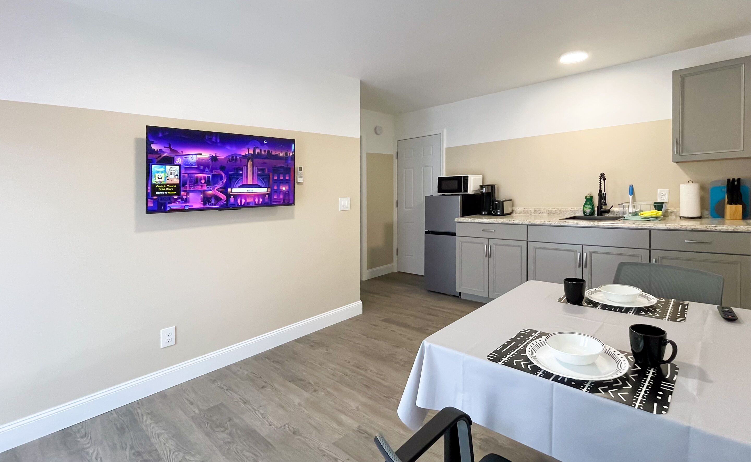 Una cocina moderna con refrigerador, microondas y una zona de comedor con una mesa dispuesta para dos.