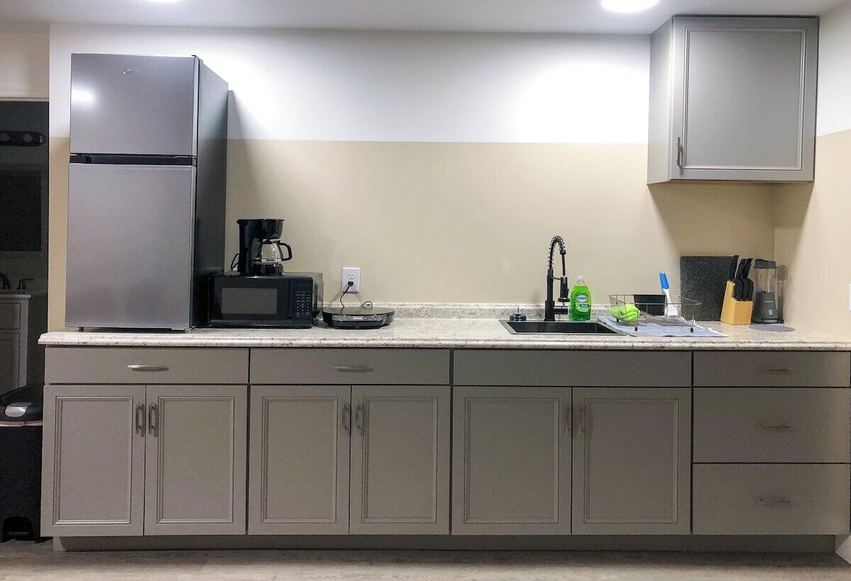 A kitchen with a refrigerator, microwave, coffee maker, sink, and cabinets.