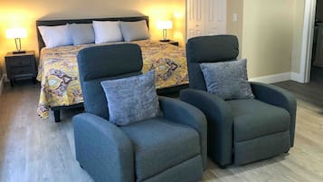Een slaapkamer met een bed, twee fauteuils, een nachtkastje en een bedlamp.
