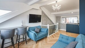 A modern loft apartment with a large open living area, a kitchen with a window, and a staircase leading to an upper floor. - Host & Stay | Wadsworth Cottage (Whitby)