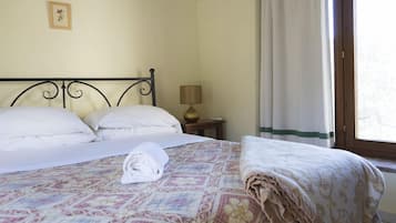 Un lit bien fait, avec une couvre-lit à motifs, une serviette pliée et une lampe sur une table de chevet.