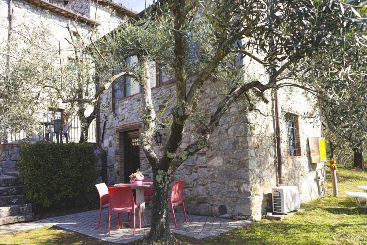 An outdoor seating area with stone walls, a tree, and a table with chairs.