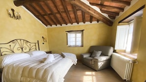 Een slaapkamer met een bed, een stoel, een raam en een radiator.