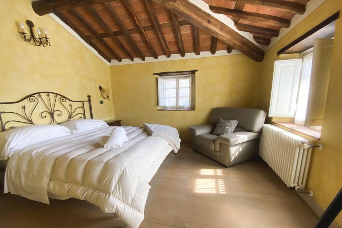 A bedroom with a bed, a chair, a window, and a radiator.