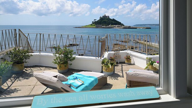 A balcony with a view of the sea and a castle on a distant island.