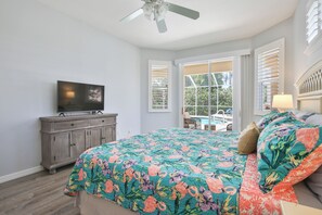 A bedroom with a bed, a TV on a dresser, and a view of the outdoors.