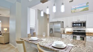 Cocina moderna con armarios blancos, electrodomésticos de acero inoxidable y encimera de granito.