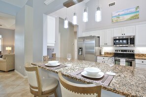 Cocina moderna con armarios blancos, electrodomésticos de acero inoxidable y encimera de granito.