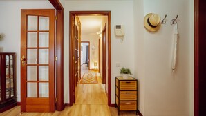 Un pasillo con piso de madera, alfombra estampada y un mueble de madera con cajones.