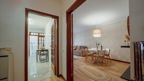 Un espacio de sala-comedor abierto con mesa, sillas, sofá y una lámpara colgante.