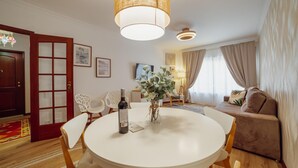 Un salón luminoso con una mesa de comedor redonda, un sofá y un televisor.