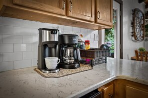 Eine Küche mit Kaffeemaschine, einer Tasse und einem Korb auf der Arbeitsfläche.