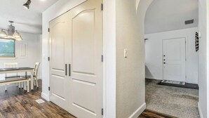 Ein Zimmer mit einem großen weißen Kleiderschrank, einem Esstisch mit Stühlen und einem Teppichboden mit einer Tür.