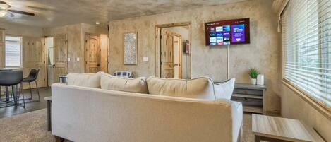 En modern hotellobby med en beige soffa, en platt-TV som är monterad på väggen och ett litet bord.