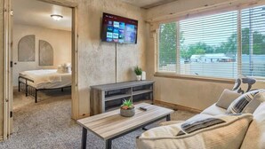 Un saló modern amb televisió plana, un sofà, una taula de centre i un llit a l'habitació veïna.