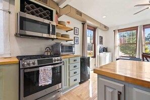 A kitchen with a stove, oven, microwave, and a wooden countertop.