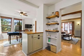 A kitchen with wooden cabinets, a dining area with a table and chairs, and a living room with a sofa and coffee table.