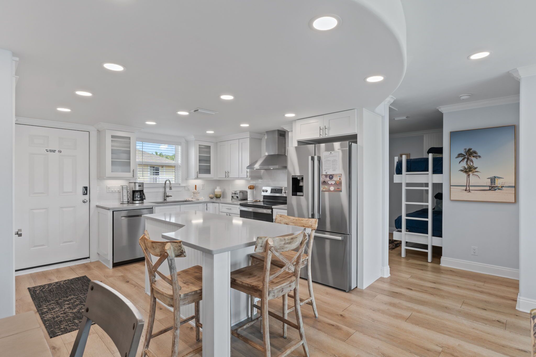 A modern kitchen with white cabinets, stainless steel appliances, and a central island with bar stools.