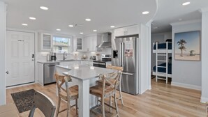 Una cocina moderna con armarios blancos, electrodomésticos de acero inoxidable y una isla central con taburetes de bar.