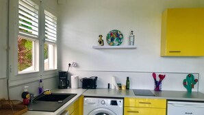 Une cuisine compacte équipée d’un lave-linge, d’une machine à café et d’un évier.