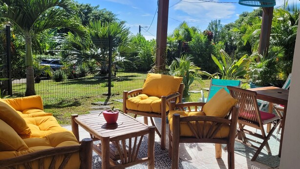 Un espace patio aménagé avec du mobilier en bois et offrant une vue sur un jardin luxuriant.