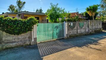 Un lotissement résidentiel fermé, avec une allée pavée, un portail en métal vert et une maison avec un toit en tuiles.