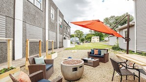Un espace extérieur aménagé en terrasse, avec des meubles en osier, un foyer et une table en bois.