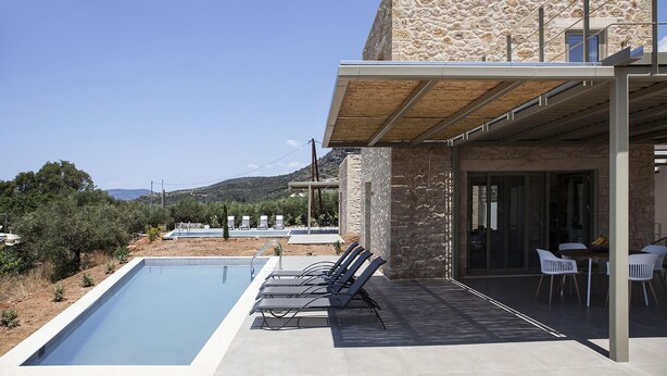 A modern villa with a swimming pool, outdoor seating, and a stone facade.