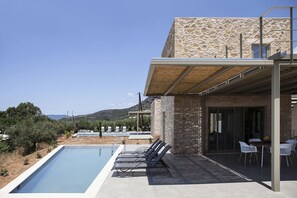 Une villa moderne dotée d’une piscine, d’un espace extérieur aménagé et d’une façade en pierre.