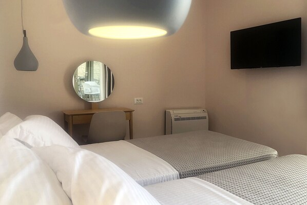 A hotel room with a bed, a desk, a mirror, a TV, and an air conditioner. - Riverstone villa 2 with private pool close to Kalogria beach (Stoupa)