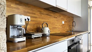 Une cuisine moderne dotée d’un plan de travail en bois, d’une machine à café, d’une bouilloire et d’un lave-vaisselle.
