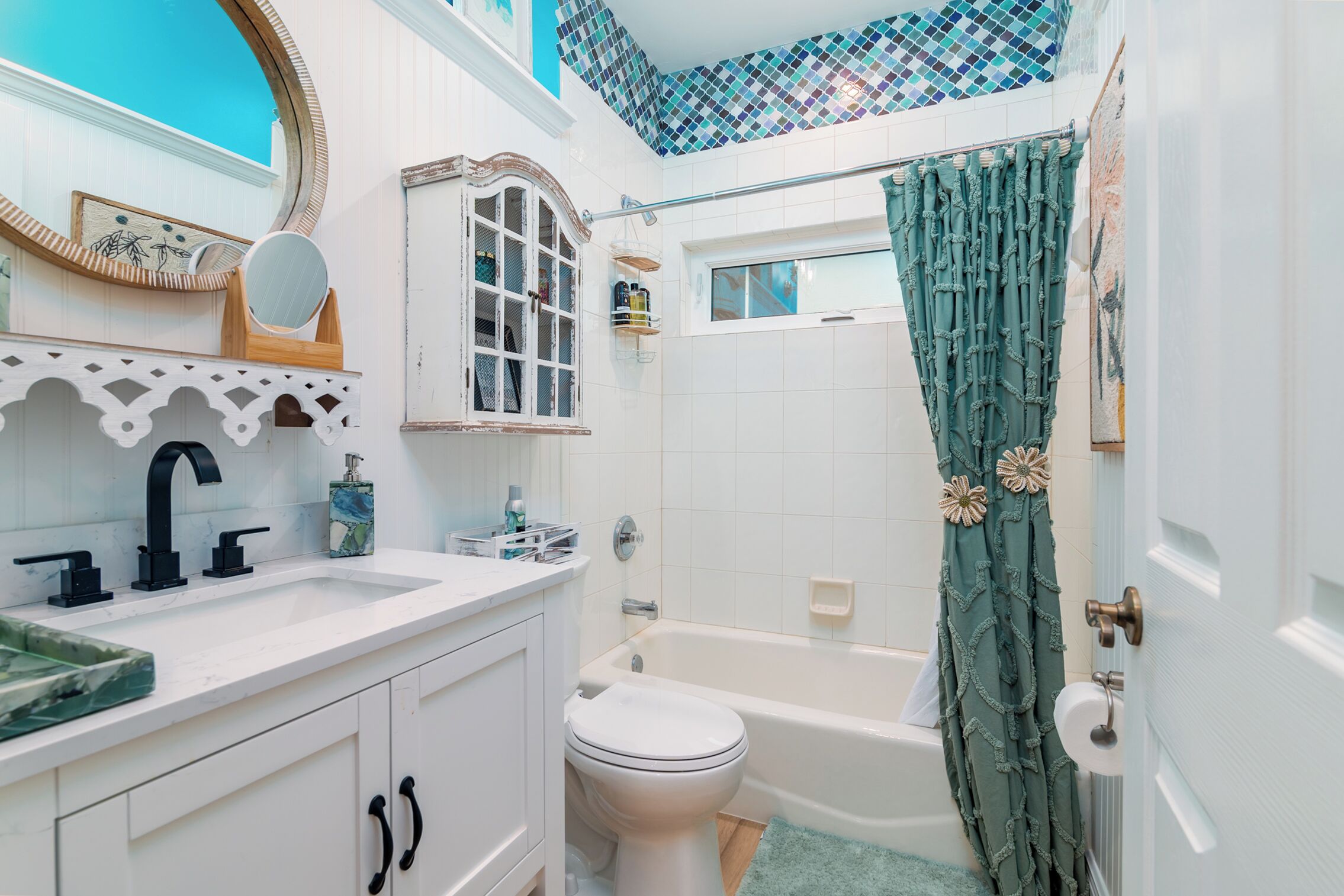 A bathroom with a white sink, a toilet, a bathtub, and a shower curtain.
