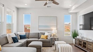 A modern living room with a sectional sofa, ottomans, a TV, and a painting. - Red Rock Retreat 5 Bedroom Home (Washington)