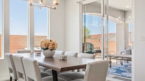 A dining area with a large table, chairs, a chandelier, and a view of the outdoors. - Red Rock Retreat 5 Bedroom Home (Washington)