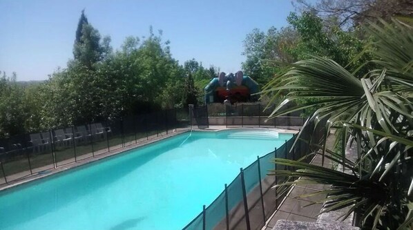 A swimming pool with a diving board and a fence.