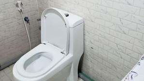 Et hvidt toilet i et badeværelse med hvide marmorfliser på vægge og gulv.