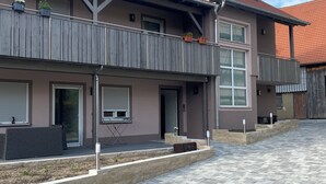 A two-story building with a balcony, a satellite dish, and a paved courtyard.