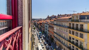 Straßenansicht mit mehrstöckigen Gebäuden, blauem Himmel und einem sichtbaren Baukran.