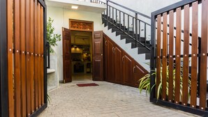 A hallway with a wooden gate, a staircase, and a kitchen area visible through an open door. - Younger Villa (Ahangama)