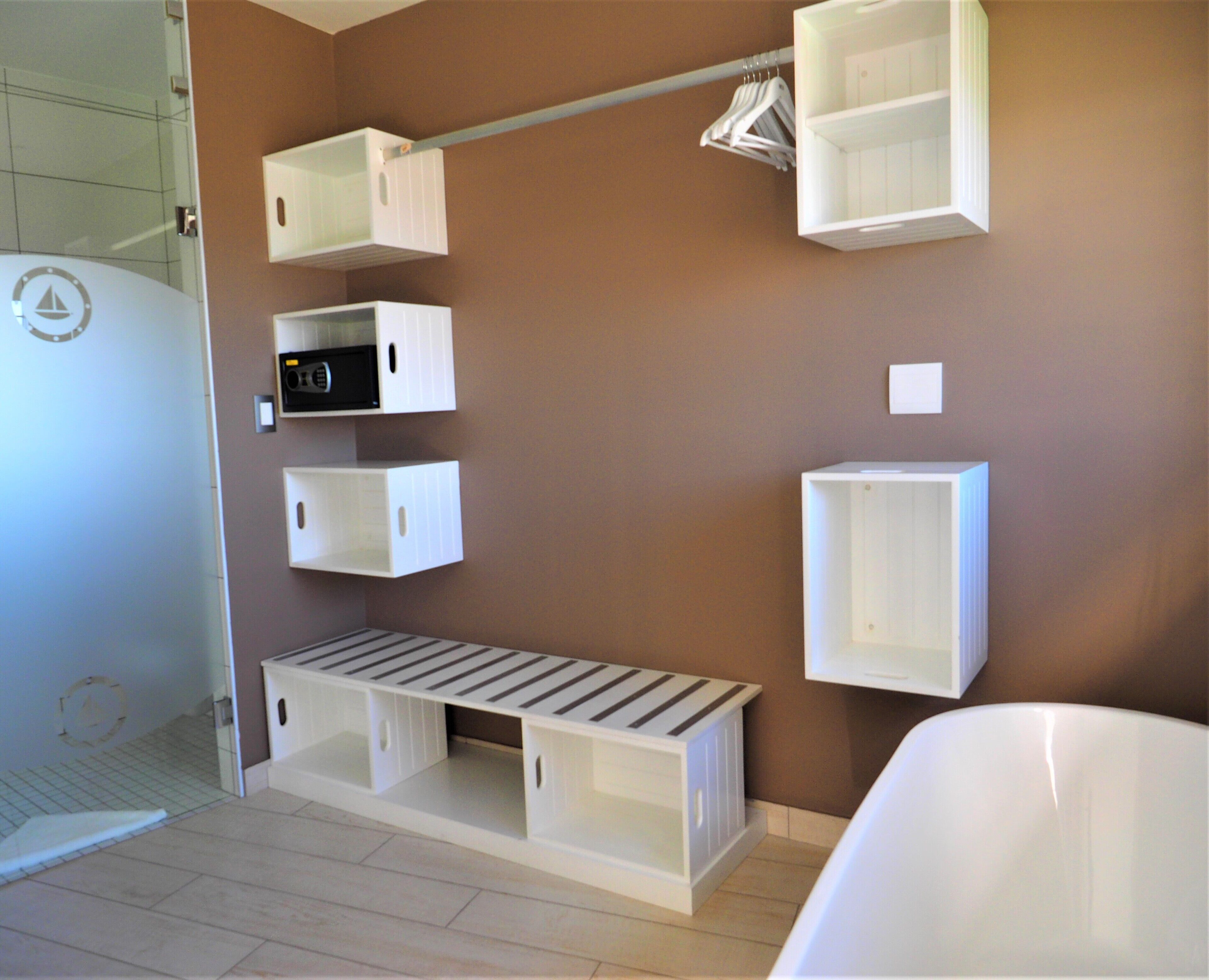 A bathroom with white storage cabinets, a towel rack, and a shower area.